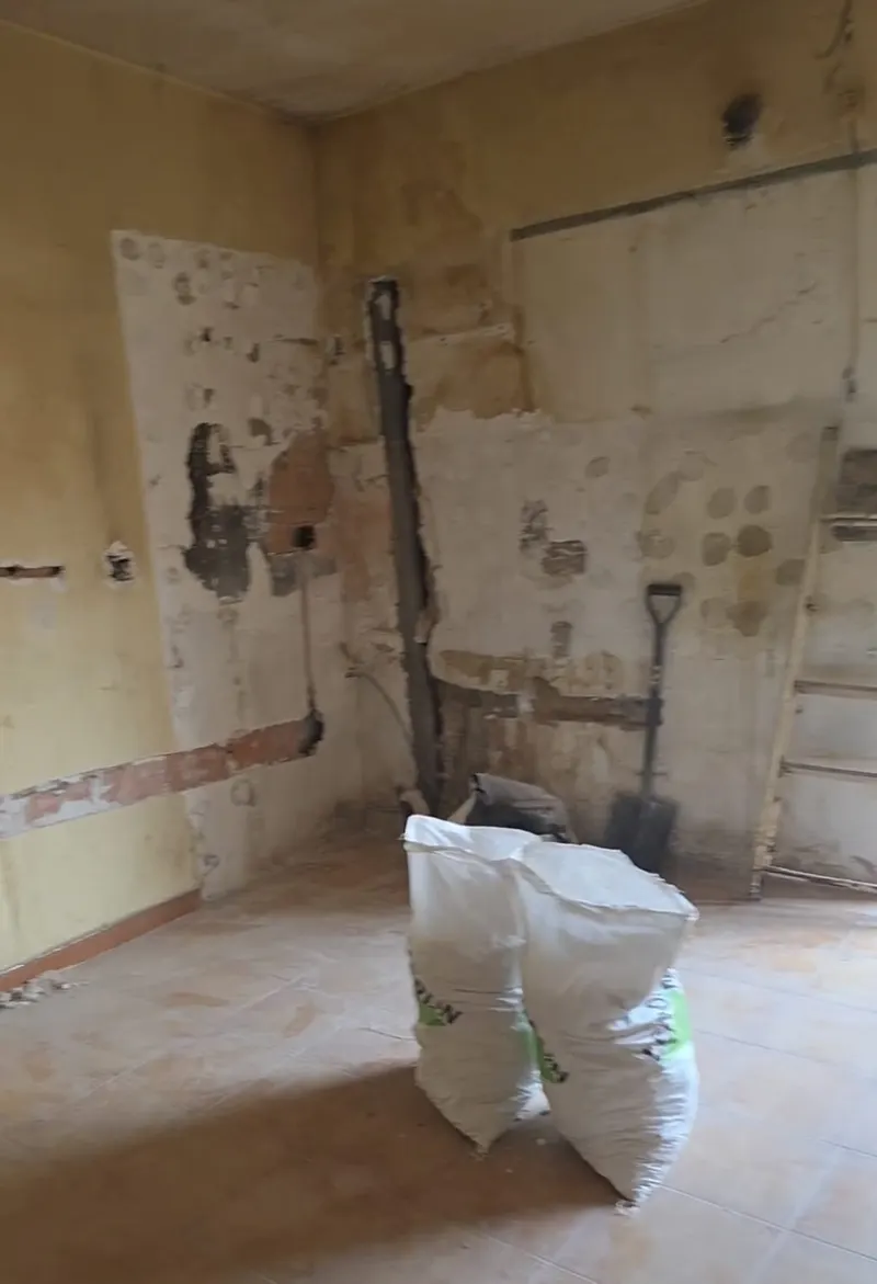 Estancia con las paredes descarnadas, rozas abiertas y sacos de escombro